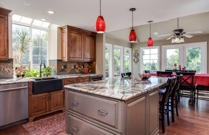Large kitchen island with a granite countertop, wood cabinets and pendant lights